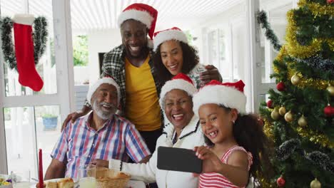 Fröhliche-Afroamerikanische-Familie-Mit-Mehreren-Generationen,-Die-Weihnachtsmützen-Trägt-Und-Ein-Urlaubs-Selfie-Macht