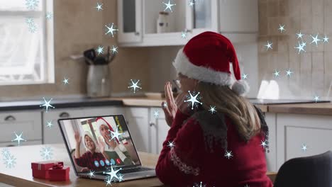 Animation-of-snow-falling-over-caucasian-woman-in-santa-hat-on-laptop-video-call-at-christmas