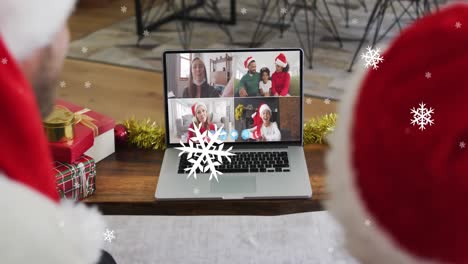 Animation-of-snow-over-smiling-caucasian-father-and-son-in-santa-hats-on-christmas-laptop-video-call