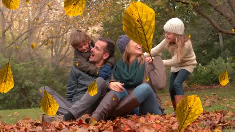 Animation-of-orange-autumn-leaves-falling-over-happy-caucasian-family-in-park