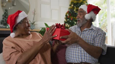 Animation-Eines-Glücklichen-Afroamerikanischen-Seniorenpaares,-Das-Zur-Weihnachtszeit-Geschenke-Teilt