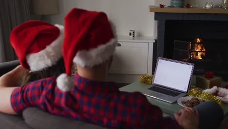 Rückansicht-Eines-Kaukasischen-Paares-Mit-Weihnachtsmützen-Und-Laptop-Mit-Kopierplatz-Auf-Dem-Bildschirm
