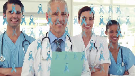 Animation-of-blue-cancer-ribbons-over-smiling-diverse-team-of-female-and-male-doctors