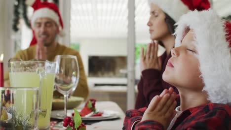Focused-caucasian-son-and-parents-praying-together-before-christmas-dinner