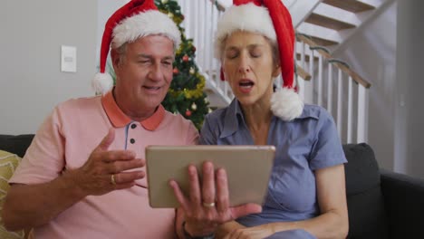 Happy-caucasian-senior-couple-having-video-call-at-christmas-time