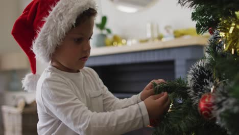Niño-Caucásico-Con-Gorro-De-Papá-Noel-Decorando-El-árbol-De-Navidad
