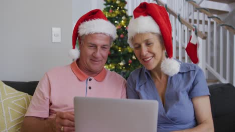 Happy-caucasian-senior-couple-having-video-call-at-christmas-time