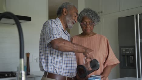 Animation-of-african-american-senior-couple-making-coffee-and-talking-together-in-kitchen