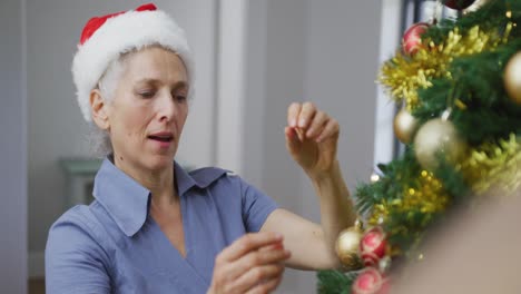 Kaukasische-ältere-Frau-Mit-Weihnachtsmütze,-Die-Den-Weihnachtsbaum-Schmückt
