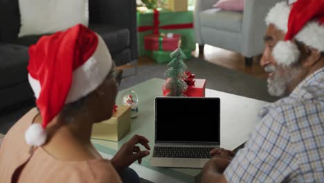 Animation-Eines-Afroamerikanischen-Seniorenpaares,-Das-Zur-Weihnachtszeit-Einen-Laptop-Mit-Kopierplatz-Auf-Dem-Bildschirm-Benutzt
