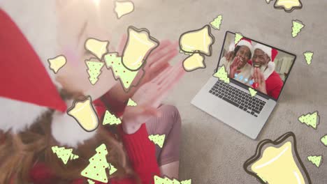 Animation-of-christmas-cookies-over-caucasian-woman-in-santa-hat-on-laptop-video-call-with-family