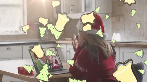 Animation-of-christmas-cookies-over-caucasian-woman-in-santa-hat-on-laptop-video-call-with-family