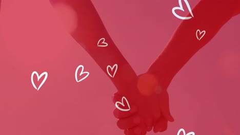 Animation-of-white-hearts-over-caucasian-couple-holding-hands