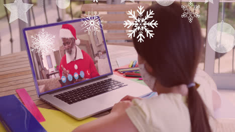 Animation-of-snow-falling-over-girl-with-face-mask-on-laptop-video-call-with-santa-at-christmas
