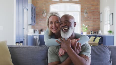 Portrait-of-mixed-race-senior-couple-hugging-each-other-and-smiling-at-home