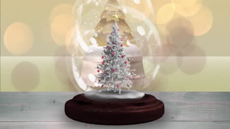 Animation-of-snow-falling-and-glowing-spots-over-snow-globe-with-tree-on-yellow-background