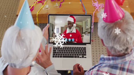 Animation-of-snow-falling-text-over-senior-caucasian-couple-on-laptop-video-call-at-christmas
