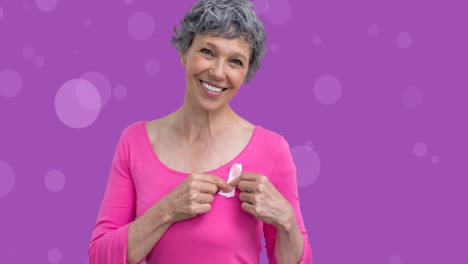 Animation-of-smiling-senior-caucasian-woman-holding-pink-ribbon-on-purple-background