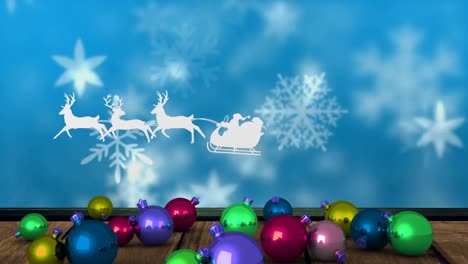 Animation-of-santa-claus-in-sleigh-with-reindeer-over-snow-falling-and-christmas-baubles,-on-blue