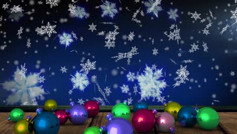 Animation-of-snow-falling-over-colorful-christmas-baubles-on-blue-background