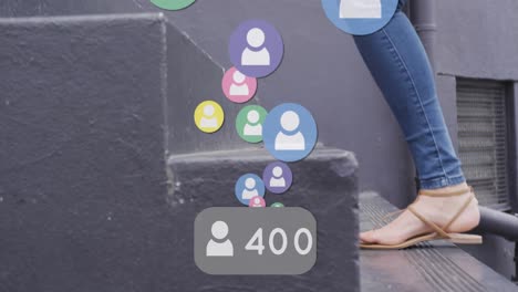 Animation-of-social-media-icons-floating-over-woman-walking-up-stairs