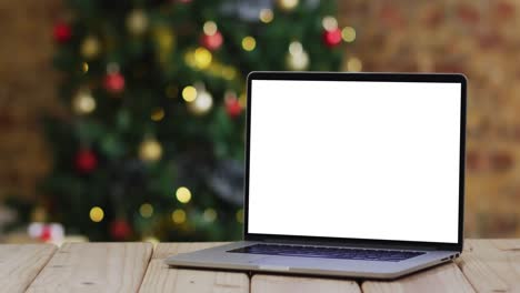 Laptop-with-copy-space-on-screen,-with-christmas-decorations-and-tree