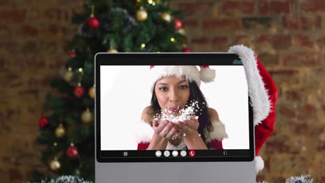 Caucasian-woman-in-santa-costume-on-video-call-on-computer,-with-christmas-decorations-and-tree