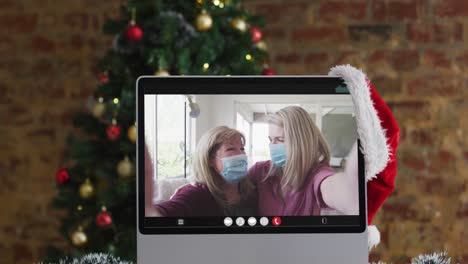 Mother-and-daughter-in-face-masks-on-video-call,-with-christmas-tree