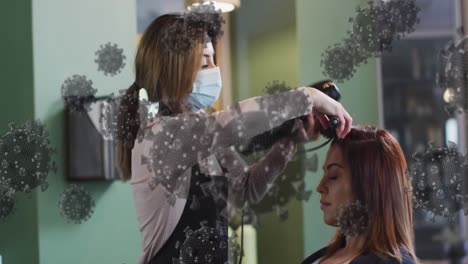 Animation-of-coronavirus-cells-over-caucasian-female-hairdresser-and-woman-wearing-face-mask