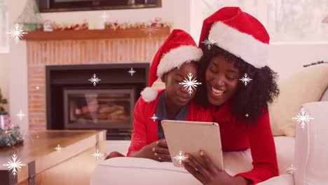 Animation-of-snow-falling-over-african-american-mother-with-son-using-tablet-at-christmas