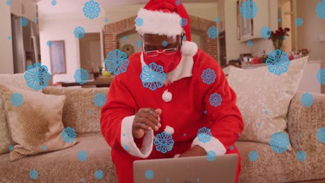 Animation-of-snow-falling-over-african-american-man-having-video-call-at-christmas