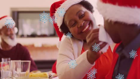 Animation-of-snow-falling-over-happy-african-american-family-during-dinner-at-christmas