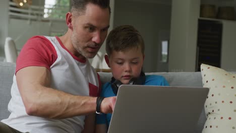 Kaukasischer-Vater-Mit-Sohn-Sitzt-Im-Wohnzimmer-Und-Benutzt-Laptop