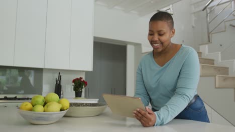 Glückliche-Afroamerikanische-Plus-Size-Frau,-Die-In-Der-Küche-Ein-Tablet-Benutzt