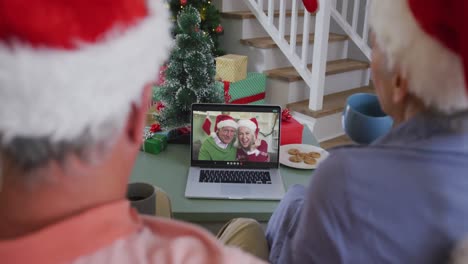 Happy-caucasian-senior-couple-couple-on-video-call-with-friends-at-christmas-time