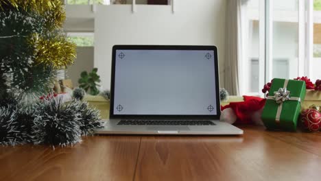 Close-up-of-laptop-with-copy-space-on-screen,-sitting-on-table-in-living-room-at-christmas