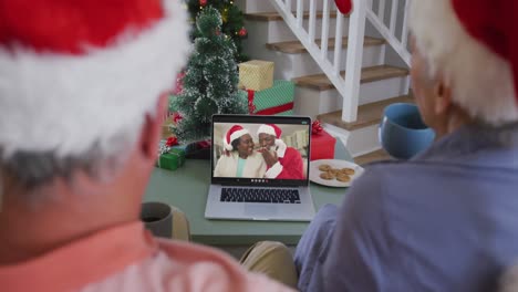 Happy-caucasian-senior-couple-couple-on-video-call-with-friends-at-christmas-time