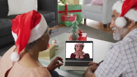 Happy-senior-african-american-couple-on-video-call-with-female-friend-at-christmas-time