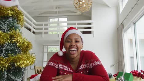 Happy-african-american-plus-size-woman-wearing-santa-claus-hat,-making-video-call-at-christmas