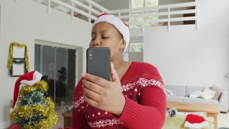 Fröhliche-Afroamerikanische-Plus-Size-Frau-Mit-Weihnachtsmütze,-Die-Zu-Weihnachten-Einen-Videoanruf-Auf-Dem-Smartphone-Tätigt