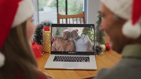 Caucasian-adult-daughter-and-senior-father-on-video-call-wit-senior-friends-at-christmas-time
