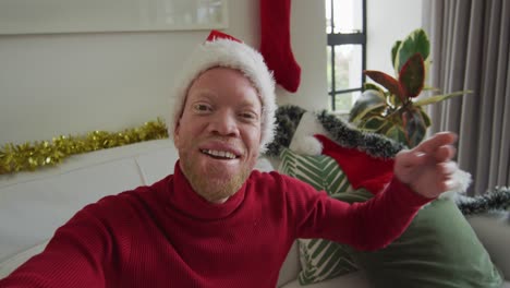 Glücklicher-Afroamerikanischer-Albino-Mann-Mit-Weihnachtsmütze,-Der-Zu-Weihnachten-Einen-Videoanruf-Macht