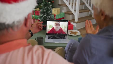Happy-caucasian-senior-couple-on-video-call-on-laptop-with-santa-claus-at-christmas-time