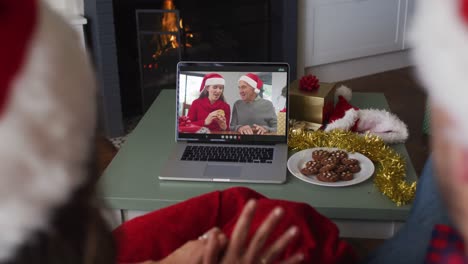 Caucasian-couple-on-video-call-on-laptop-with-grandparents-at-christmas-time