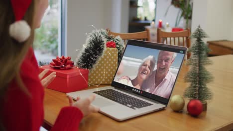 Kaukasische-Frau-Mit-Weihnachtsmütze,-Die-Zu-Weihnachten-Zu-Hause-Einen-Videoanruf-Auf-Dem-Laptop-Führt
