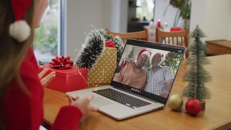 Happy-caucasian-woman-on-video-call-with-senior-couple-at-christmas-time