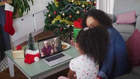 Happy-african-american-mother-and-daughter-on-video-call-on-laptop-with-friends-at-christmas