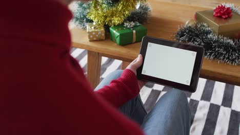 Happy-albino-african-american-man-wearing-santa-hat-using-tablet-with-copy-space-at-christmas