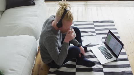 Albino-african-american-man-with-dreadlocks-siting-on-the-floor,-working-and-using-laptop