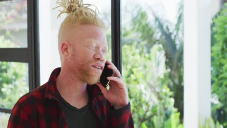 Hombre-Afroamericano-Albino-Con-Rastas-Usando-Un-Teléfono-Inteligente-Y-Mirando-La-Ventana